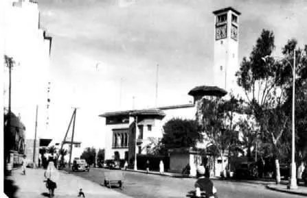 Carte postale ancienne : un autobus dans une rue de Casablanca, façades commerciales.